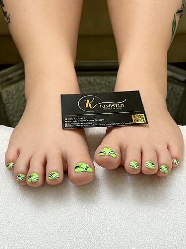 A finished pedicure with fine green and gold leaf art across the toes