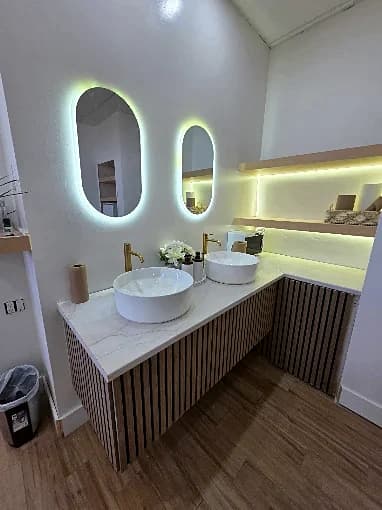 The salon's marble vanity with backlit mirrors and a slatted wood wall